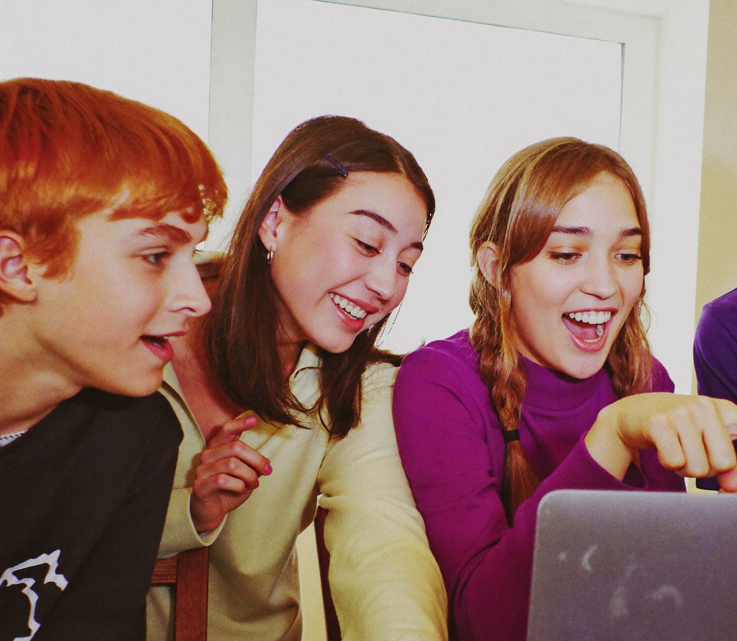 Students reacting together to something on a laptop